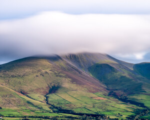 Landscape of mountains with clouds flowing over the peak