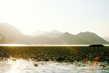 Landscape of blue deep lake in light of sun in daytime, clouds in sky, mountains