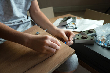 teenager assembles furniture according to instructions