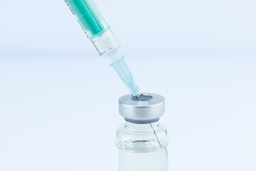 Syringe injecting liquid into a vial. Medical, healthcare, vaccination concept. Clean, sterile environment.