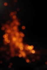 Fototapeta premium Blurred orange and yellow fire sparks against a pitch-black background , incandescent, heat, orange