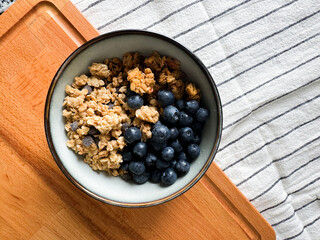 Healthy breakfast bowl with granola and fresh blueberries on wooden surface