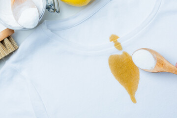 A person hand powder on a yellow stain on with baking soda. DIY cleaning method using natural products to remove stains. top view