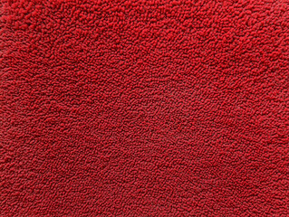 Fototapeta premium Vibrant red textured fabric fills the frame, showcasing its soft and plush surface under bright light