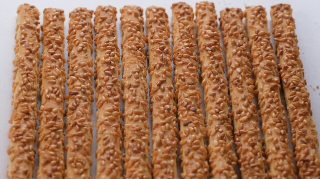 Top view. Crispy pretzel sticks coated with sesame seeds. Breadstick. Slider shot. Shallow depth of field, selective focus. Snack food, bakery, culinary, appetizer contents. 4k