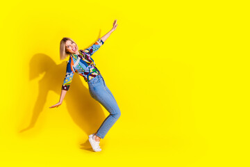 Full size photo of pretty young girl dancing have fun tiptoes wear trendy colorful outfit isolated on yellow color background