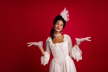 A young woman in an elegant baroque gown poses gracefully against a vibrant red backdrop