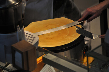 A person's hand preparing the dough to make a crepe, food business