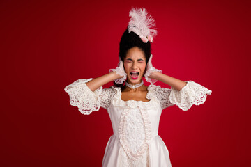 Young woman dressed in baroque costume expressively posing against a vivid red background, blending historic elegance with a modern twist.