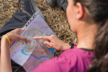Woman using compass and map during orienteering race. Latin young venezuelan