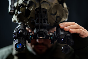 A soldier using modern binocular night vision in the darkness. Close up.