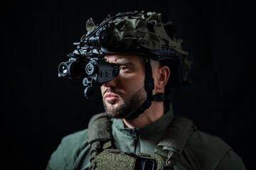 A special force soldier using modern binocular night vision in the darkness. Close up.