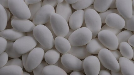 Top down view. Heap of white chocolate covered almond nuts. Glazed white dragees. Slider shot. Candies, sweet treats, snacks, confectionery concepts. 4k