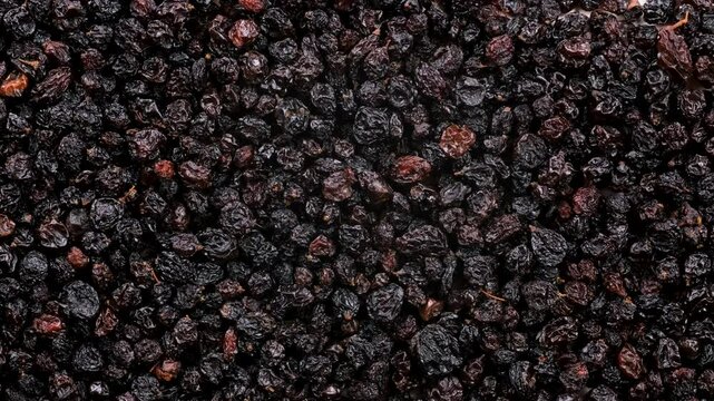 Top down view. Heap of black colored dried raisins, slider shot. Dried fruits, healthy lifestyles. Nutrition, snacks, organic food concepts. 4k.
