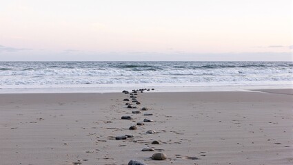 Fototapeta premium Tranquil beach with stone path ocean waves and pastel sunset