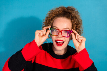 Young woman in colorful glasses and striped sweater posing against a blue background