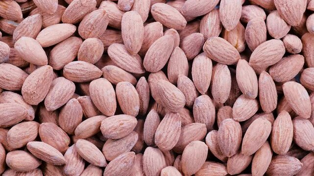Top down view, heap of fresh almonds. Natural brown tones and textured shells. Slider shot. Food, nutrition, healthy eating, snacks, ingredient concepts. 4k