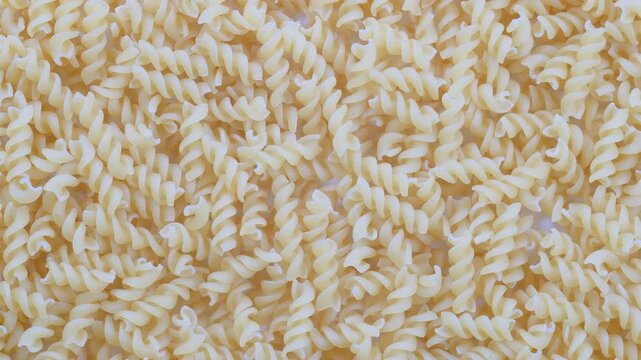 Top down view. Pile of uncooked Fusilli, italian spiral pasta. Slider shot. Pasta dishes, Mediterranean food, Italian cuisine, cooking concepts. 4k