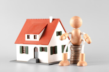 A wooden man holding coins waiting to buy a house