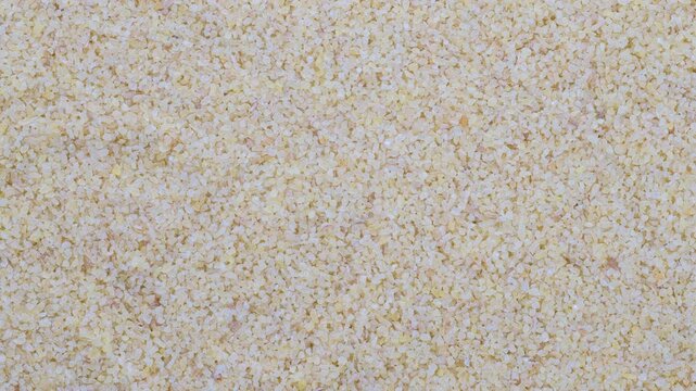 Top down view. Heap of raw uncooked bulgur grains. Slider shot. Texture of grains. Cooking, whole grains, traditional cuisine, food-related themes. 4k