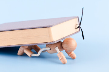 A wooden man crushed by a book