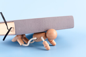 A wooden man crushed by a book