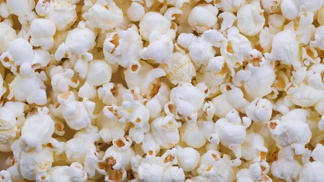 Top down view. Heap of fresh popped salty popcorn grains with crispy, fluffy appearance. Snacks and Appetizers, Movie Nights, Party Food,  Relaxation and Entertainment concepts. 4k