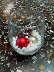 christmas centerpiece in a glass bowl with red and silver ornaments, pine cones, and white filler. Festive holiday decor