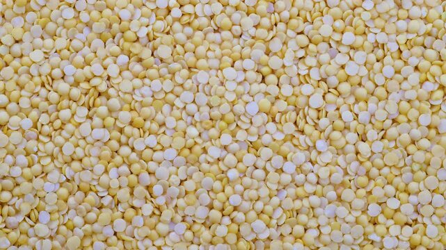 Top down view. Heap of raw uncooked yellow lentils, slider shot. Cooking, legumes, healthy eating, food preparation themes. 4k