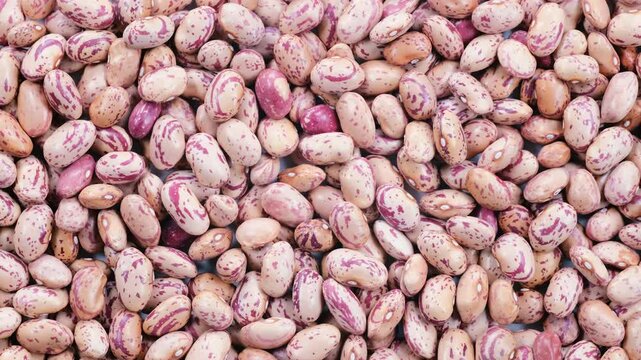 Top down view. Heap of dried uncooked speckled pinto kidney beans (barbunya), slider shot. Cooking, legumes, healthy eating, food preparation concepts. 4k
