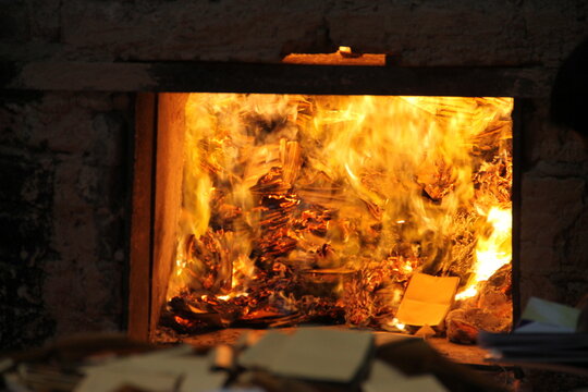 A burning furnace with papers and cardboard scattered around in a dimly lit environment.