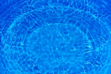 Bluewater waves on the surface ripples blurred. Defocus blurred transparent blue colored clear calm water surface texture with splash and bubbles. Water waves with shining pattern texture background.
