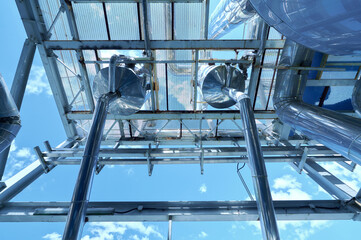 Overview of chemical plant infrastructure featuring pipelines against a clear blue sky during...