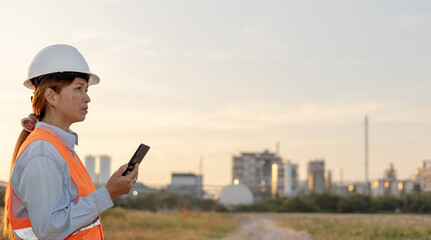 Construction Worker Monitors Site Activity at Sunset in an Urban Environment in a Safety Vest and Helmet