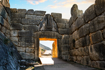 The sun sets behind the ancient Lion Gate entrance to the archaeological site of Mycenae, a Greek...