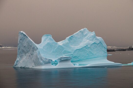 Fascinating Antarctica with a beautiful iceberg ice mountain covered with snow and ice in arctic see and low sunset