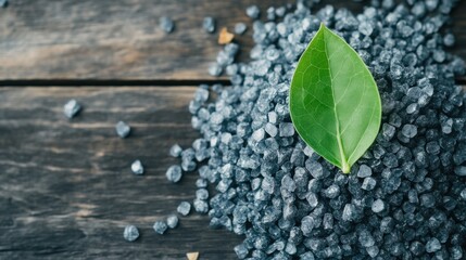 Naklejka premium Natural black salt crystals with green leaf on wooden background, perfect for culinary use and healthy seasoning alternatives.