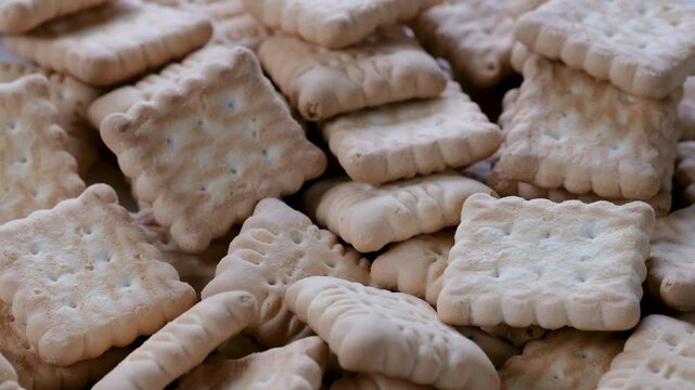 Macro view of small-sized brown petits beurre-style biscuits cracker stacked together. Slider shot. Shallow depth of field, selective focus. snacks, tea time, baked food, dessert concepts. 4k