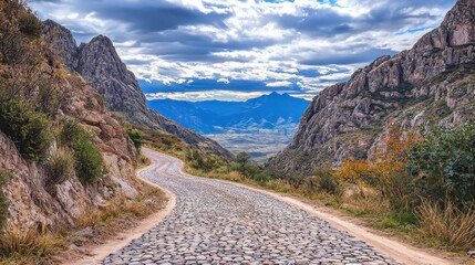 Fototapeta premium Scenic winding road through mountainous landscape under a cloudy sky.