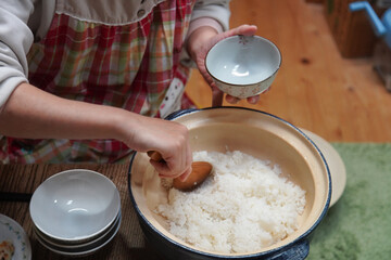土鍋で炊いたご飯をよそう女性