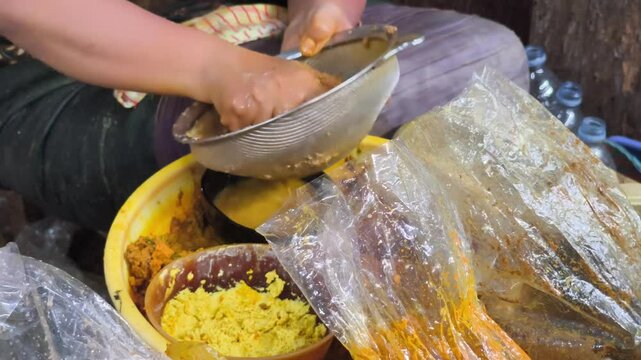 Jamu or The traditional herbal medicine seller is meticulously crafting a customised herbal concoction for a customer. Using their bare hands, they expertly blend various herbal ingredients.