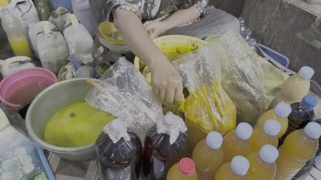 Jamu or The traditional herbal medicine seller is meticulously crafting a customised herbal concoction for a customer. Using their bare hands, they expertly blend various herbal ingredients.