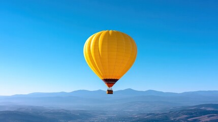Fototapeta premium A vibrant yellow hot air balloon soaring above scenic mountains.
