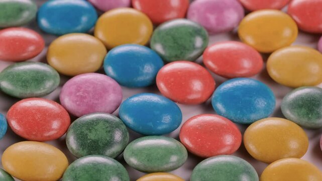 Heap of multi colored dragees. Glazed bonbon candies. Slider shot. Selective focus. Sweet treats, desserts, snacks, confectionery concepts. 4k