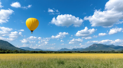 Fototapeta premium vibrant yellow hot air balloon floats over golden rice field under blue sky