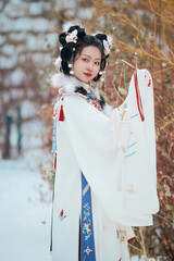 Asian girl wearing Ming Dynasty Hanfu outdoors after heavy snow