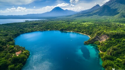 Obraz premium A serene lake view from above, showcasing vibrant blue water surrounded by lush green forests and rugged mountains