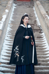 A Chinese girl dressed in Hanfu plays a martial arts hero in the snowy ancient city
