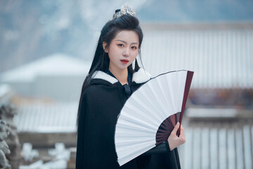 A Chinese girl dressed in Hanfu plays a martial arts hero in the snowy ancient city