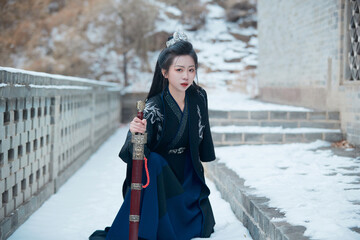 A Chinese girl dressed in Hanfu plays a martial arts hero in the snowy ancient city